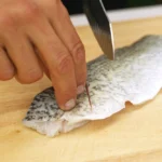 A chef scores a barramundi fillet