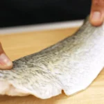 A barramundi fillet is placed on a cutting board