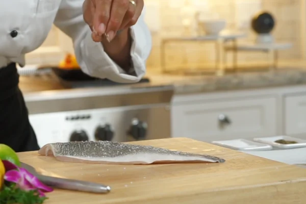 Branzino-Fillet A chef sprinkles salt on a branzino fillet