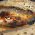 A crispy butterflied branzino fillet in a pan with caper sauce