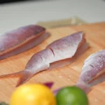 A chef sprinkles salt over butterflied snapper fillets