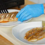 A chef plates a natural cut yellowtail snapper fillet next to a butterflied yellowtail snapper fillet to compare