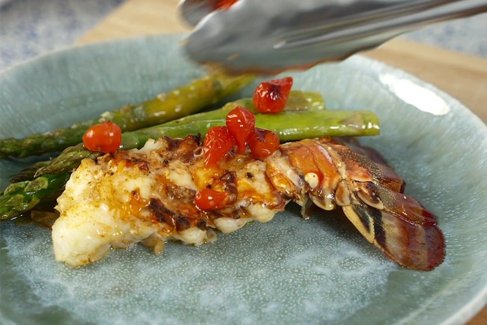 A poached lobster tail with asparagus and tomatoes