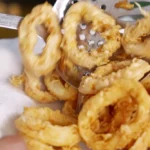 Fried calamari rings being removed from the oil