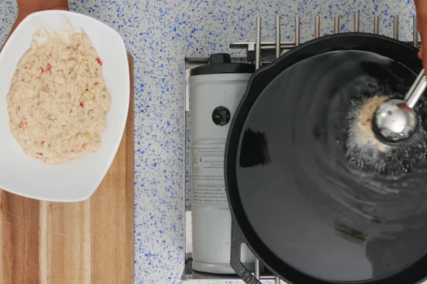 Frozen-Conch-Fritters Conch fritter batter being scooped into hot oil to fry