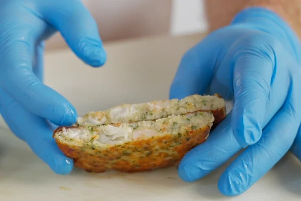 Frozen-Shrimp-Burger-Netuno A chef cuts a cooked shrimp burger to show the chunks of shrimp inside the patty