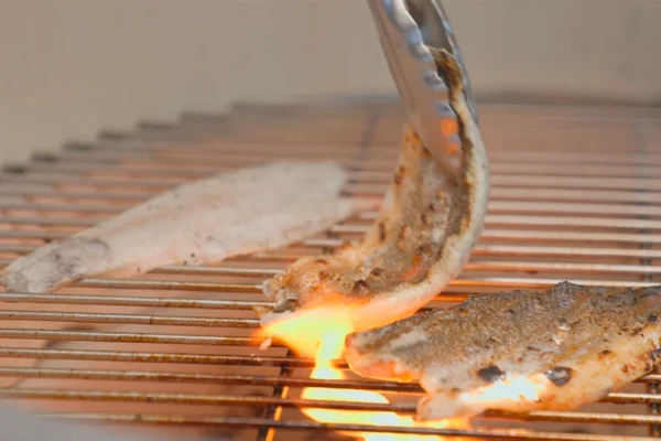 Grilled-Branzino-Fillets A chef flips branzino fillet on a grill