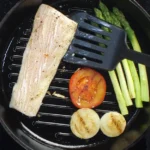 Mahi Mahi in a grill pan cooking with vegetables