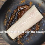 Mahi Mahi portion marinating in a dish with seasoning