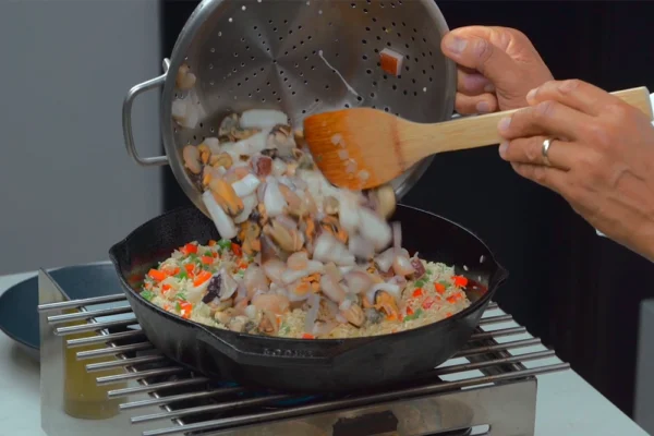 Seafood-Mix Seafood medley is added to rice that is cooking in a pot