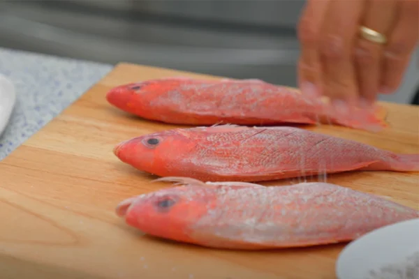 Whole-Beeliner-Vermillion-Snapper A chef salts a whole vermillion beeliner snapper
