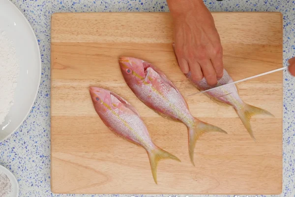 Whole-Yellowtail-Snapper-Baked A chef scores whole yellowtail snapper on a cutting board